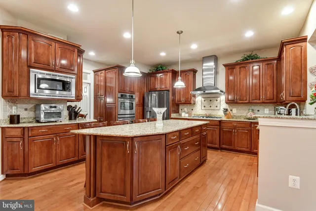 a large kitchen with stainless steel appliances wooden cabinets a stove and a center island