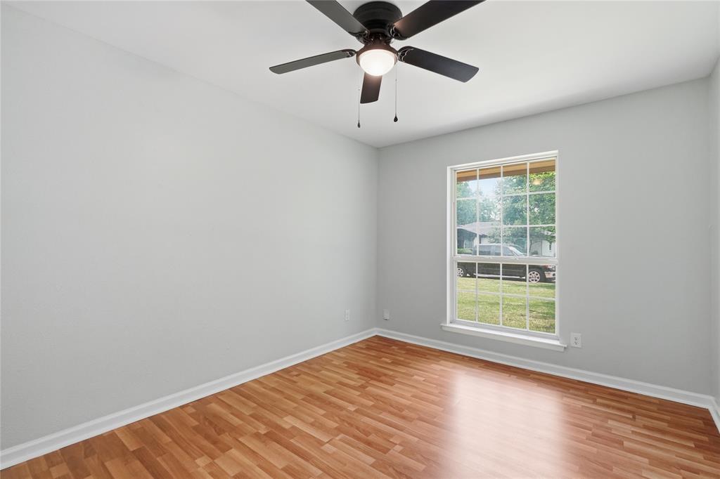 837 Springdale Road Bedford, TX 76021 - Photo 4 of 28 Light-filled interior space featuring wood-finish flooring, a contemporary ceiling fan with integrated lighting, and a multi-pane window