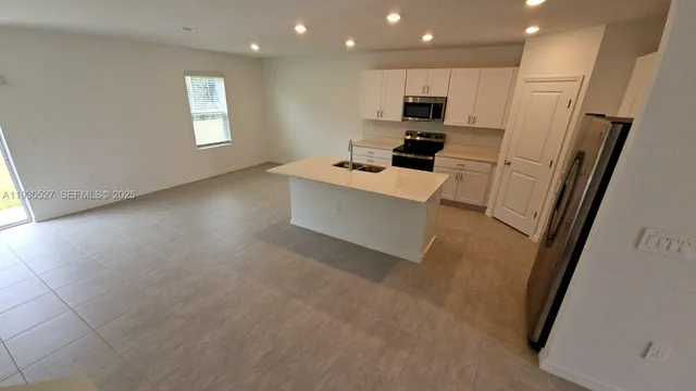 a living room with stainless steel appliances furniture a flat screen tv and a window