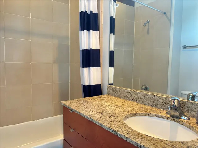 a bathroom with a granite countertop sink and a bathtub