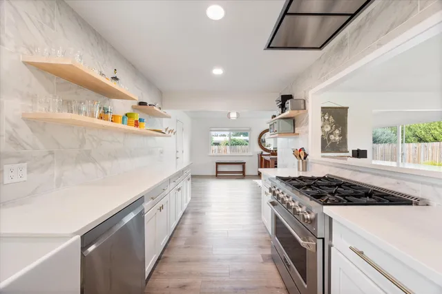 a kitchen with stainless steel appliances granite countertop a stove and a wooden floors
