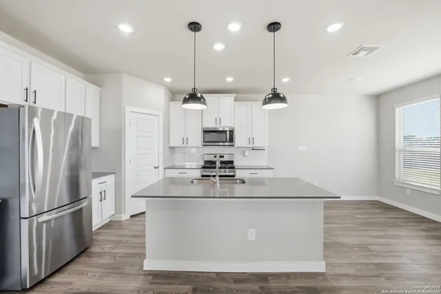 a large kitchen with stainless steel appliances granite countertop a refrigerator a sink dishwasher a stove and a refrigerator