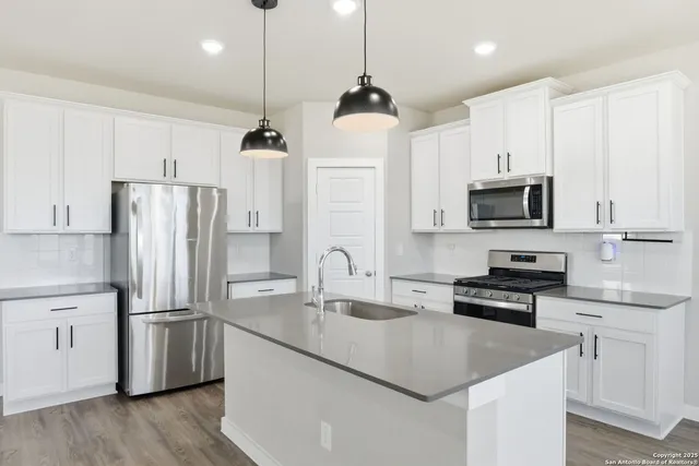 a kitchen with stainless steel appliances granite countertop a refrigerator a sink dishwasher a stove and a refrigerator with wooden floor