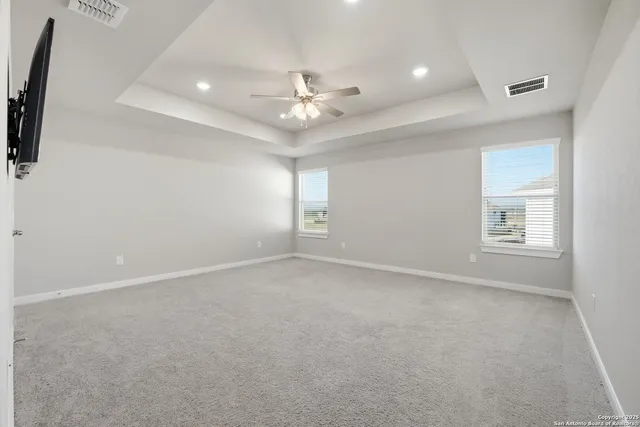 an empty room with windows and fan