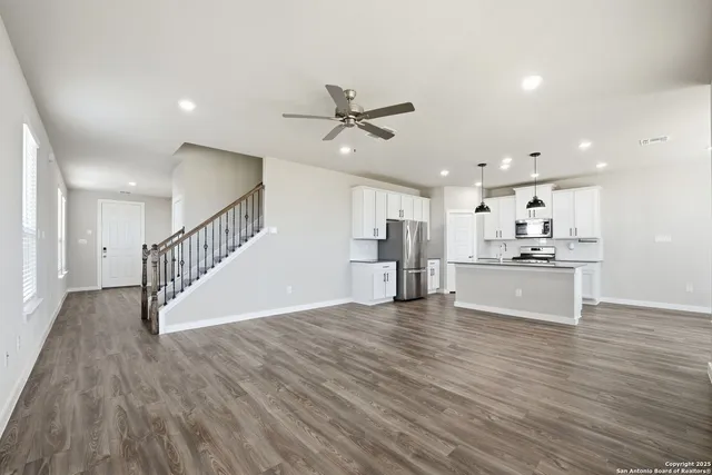 a view of an empty room and kitchen with ceiling fan kitchen view