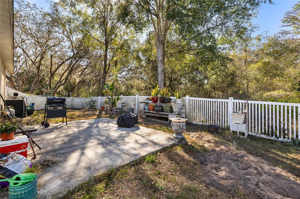12113 Deertrack Loop Spring Hill, FL 34610 - Photo 22 of 31 a view of a backyard with a large tree and wooden fence