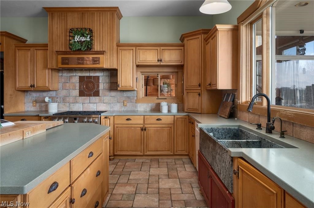 9419 Robinson Road Chardon, OH 44024 - Photo 15 of 49 Kitchen featuring wood cabinetry, stone-look countertops, a tile backsplash, and an integrated stainless steel range