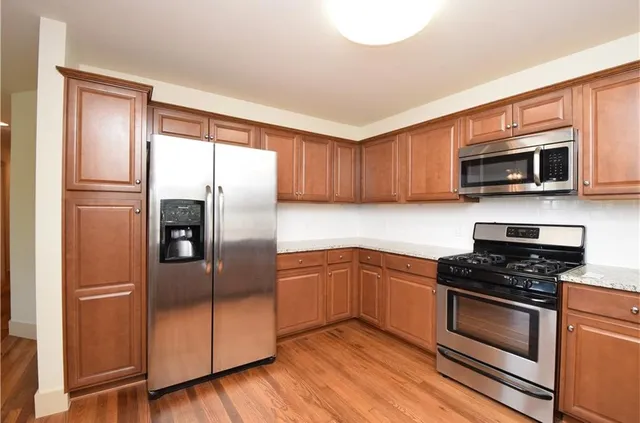 a kitchen with stainless steel appliances wooden cabinets and a refrigerator
