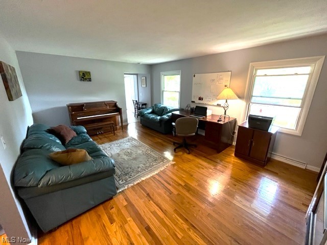 Living room with a baseboard heating unit and light hardwood floors