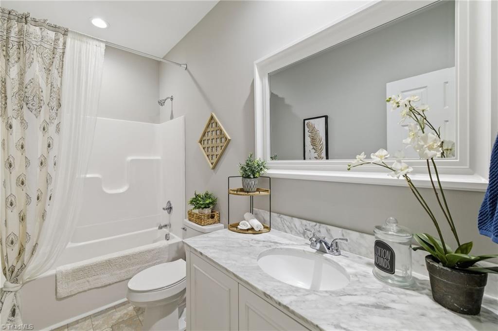626 Bethany Road Reidsville, NC 27320 - Photo 21 of 42 Hall bathroom at 626 Bethany Road, Reidsville, NC 27320, Rockingham County. Single vanity with white cabinet and marble-look countertop, tub/shower combo with decorative curtain, large framed mirror, tile floor. Bethany Community.