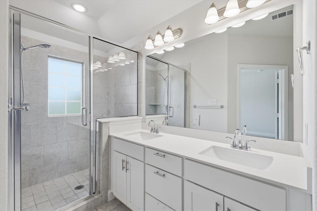 519 Sequoia Street Allen, TX 75002 - Photo 23 of 38 Modern bathroom featuring a dual vanity with white cabinetry, polished chrome fixtures, and a spacious glass-enclosed shower with tile surround