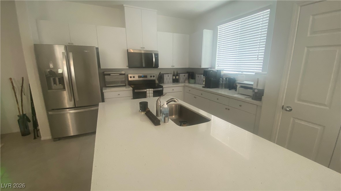 5675 Spellbinding Street Las Vegas, NV 89148 - Photo 9 of 18 Kitchen featuring appliances with stainless steel finishes, white cabinetry, and light stone counters