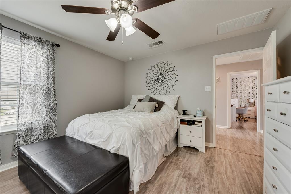 149 Cattlemans Creek Road Newark, TX 76071 - Photo 17 of 39 Primary bedroom with laminate floors, ceiling fan and barn door to ensuite bathroom at 149 Cattlemans Creek Rd in the Chisholm Springs neighborhood in Newark, TX 76071