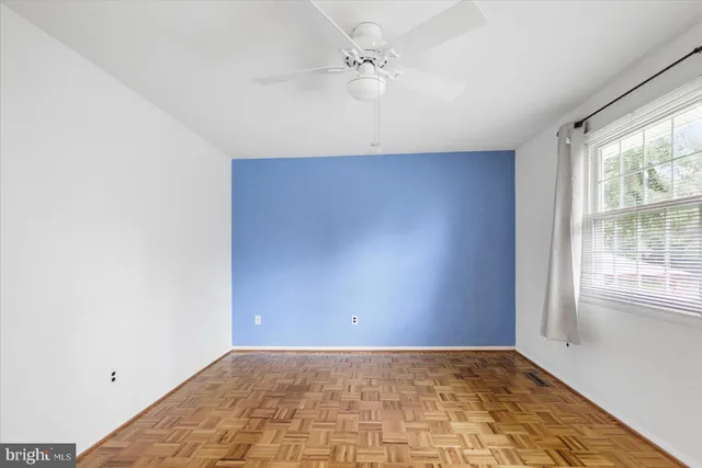 an empty room with windows and fan