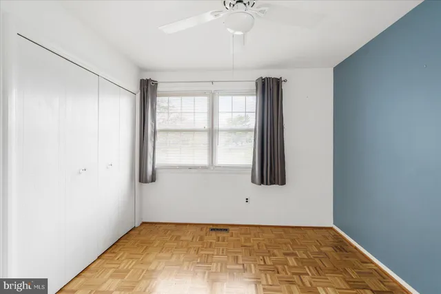 a view of an empty room with window and hardwood floor