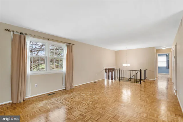 a view of an empty room with window and wooden floor