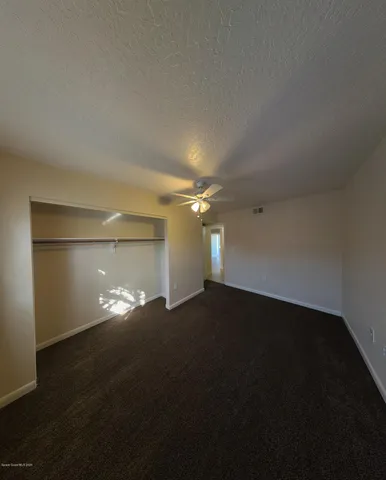 a view of an empty room with a ceiling fan and window