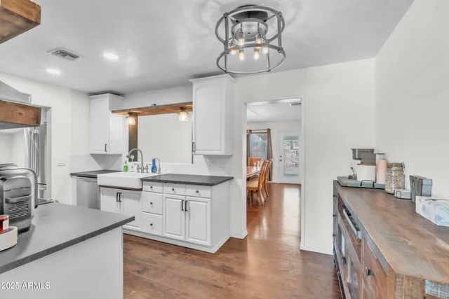 a open kitchen with stainless steel appliances granite countertop a sink stove and white cabinets with wooden floor