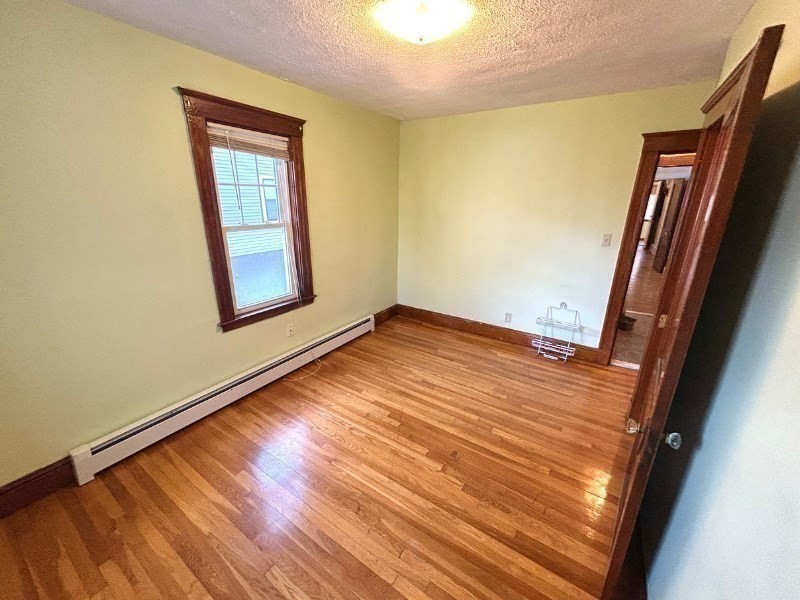 119 Bailey Road, Unit 1 Somerville, MA 02145 - Photo 11 of 25 an empty room with wooden floor and windows