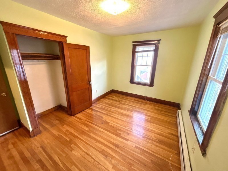 119 Bailey Road, Unit 1 Somerville, MA 02145 - Photo 13 of 25 a view of an empty room with wooden floor and a window