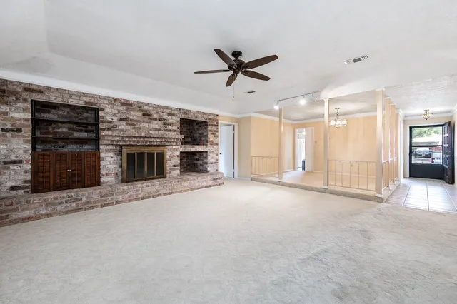 an empty room with kitchen fireplace and a ceiling fan