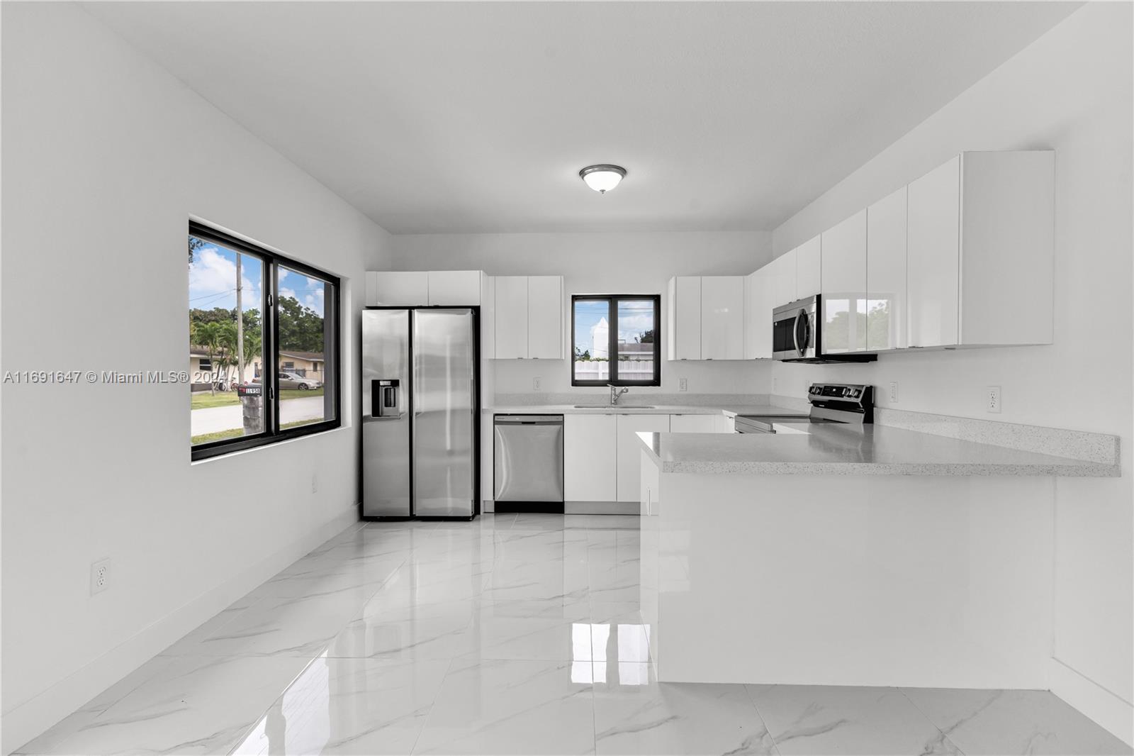 11970 Southwest 213th Street, Unit 1 Miami, FL 33177 - Photo 8 of 36 a large white kitchen with stainless steel appliances a sink a microwave a stove and white cabinets