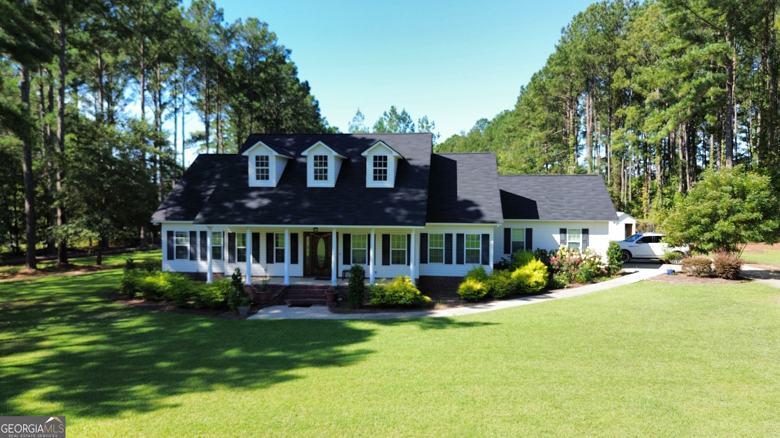 a front view of a house with garden and trees