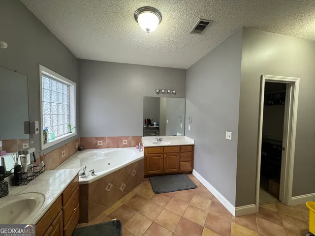 a large bathroom with a granite countertop tub sink and mirror