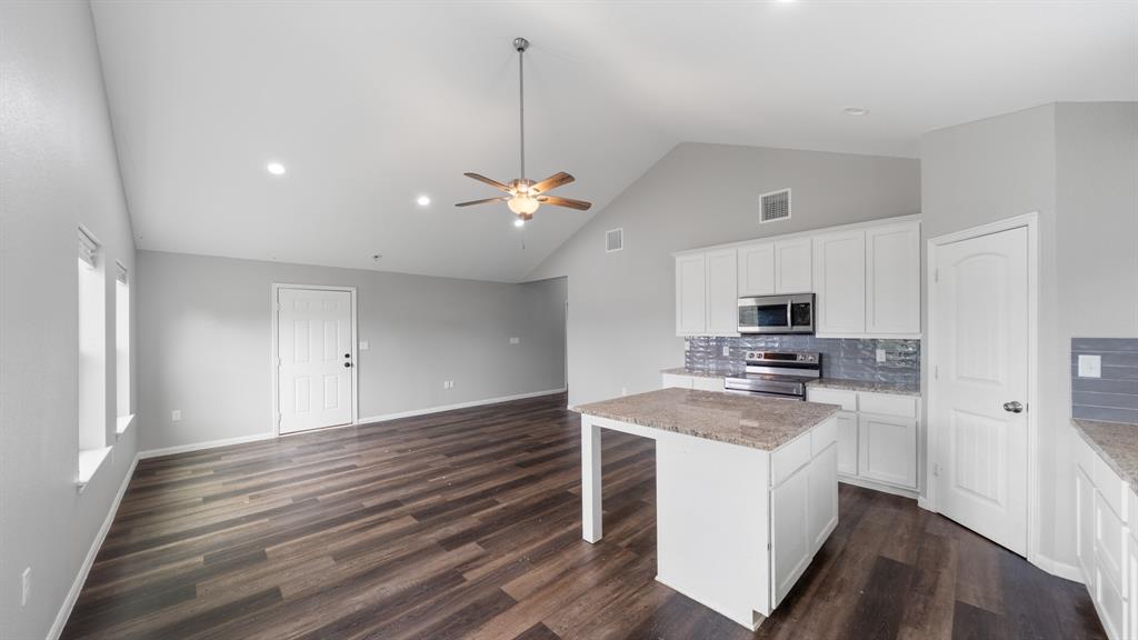 207 East McCoulskey Street Terrell, TX 75160 - Photo 6 of 29 a kitchen with stainless steel appliances a white stove top oven a sink dishwasher and a refrigerator with wooden floor