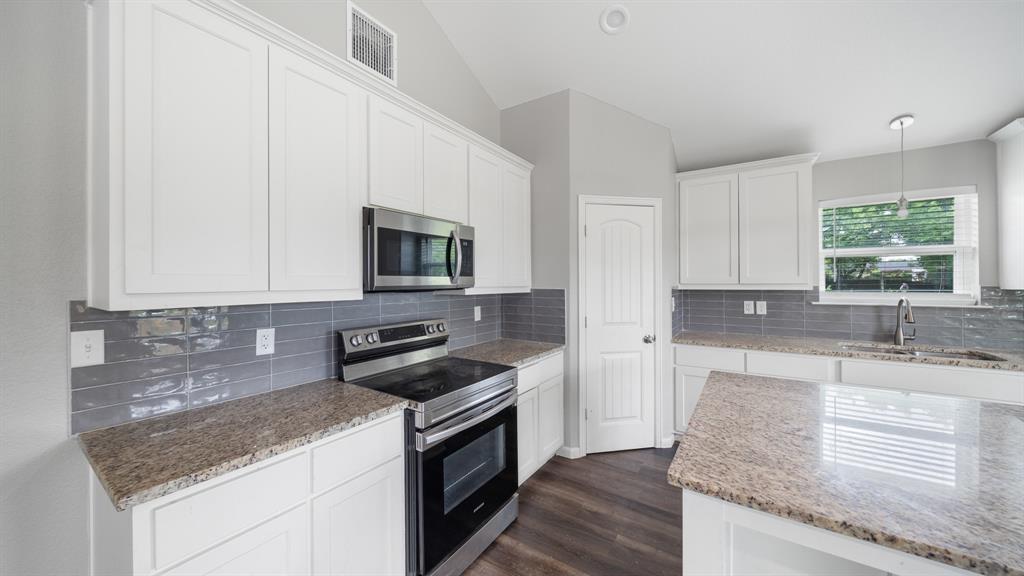 207 East McCoulskey Street Terrell, TX 75160 - Photo 8 of 29 a kitchen with granite countertop a sink and a stove top oven with wooden floor