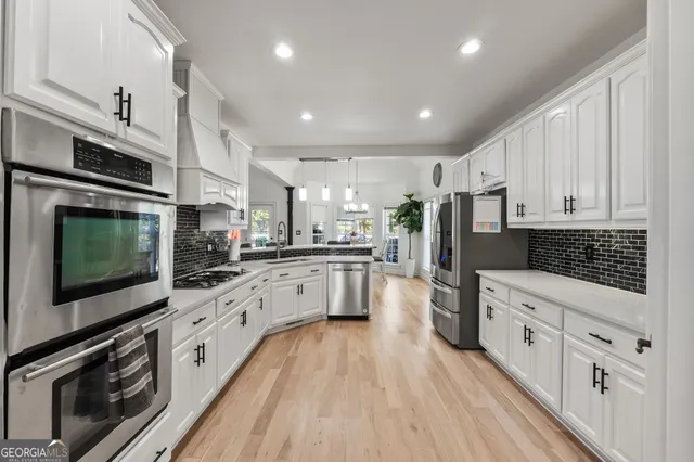 a kitchen with stainless steel appliances granite countertop a stove top oven a sink and white cabinets
