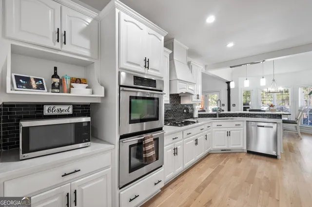 a kitchen with stainless steel appliances granite countertop a stove a sink and white cabinets