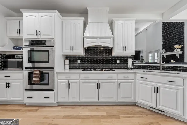 a kitchen with stainless steel appliances kitchen island granite countertop a refrigerator a stove a sink a dining table and chairs with wooden floor