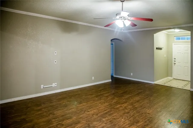 a view of an empty room with wooden floor and a chandelier