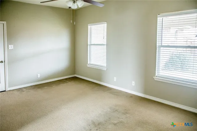 an empty room with a window and a chandelier fan