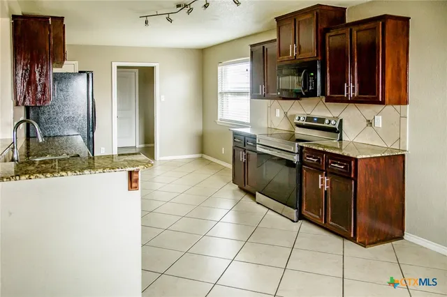 a kitchen with stainless steel appliances granite countertop a sink stove and refrigerator