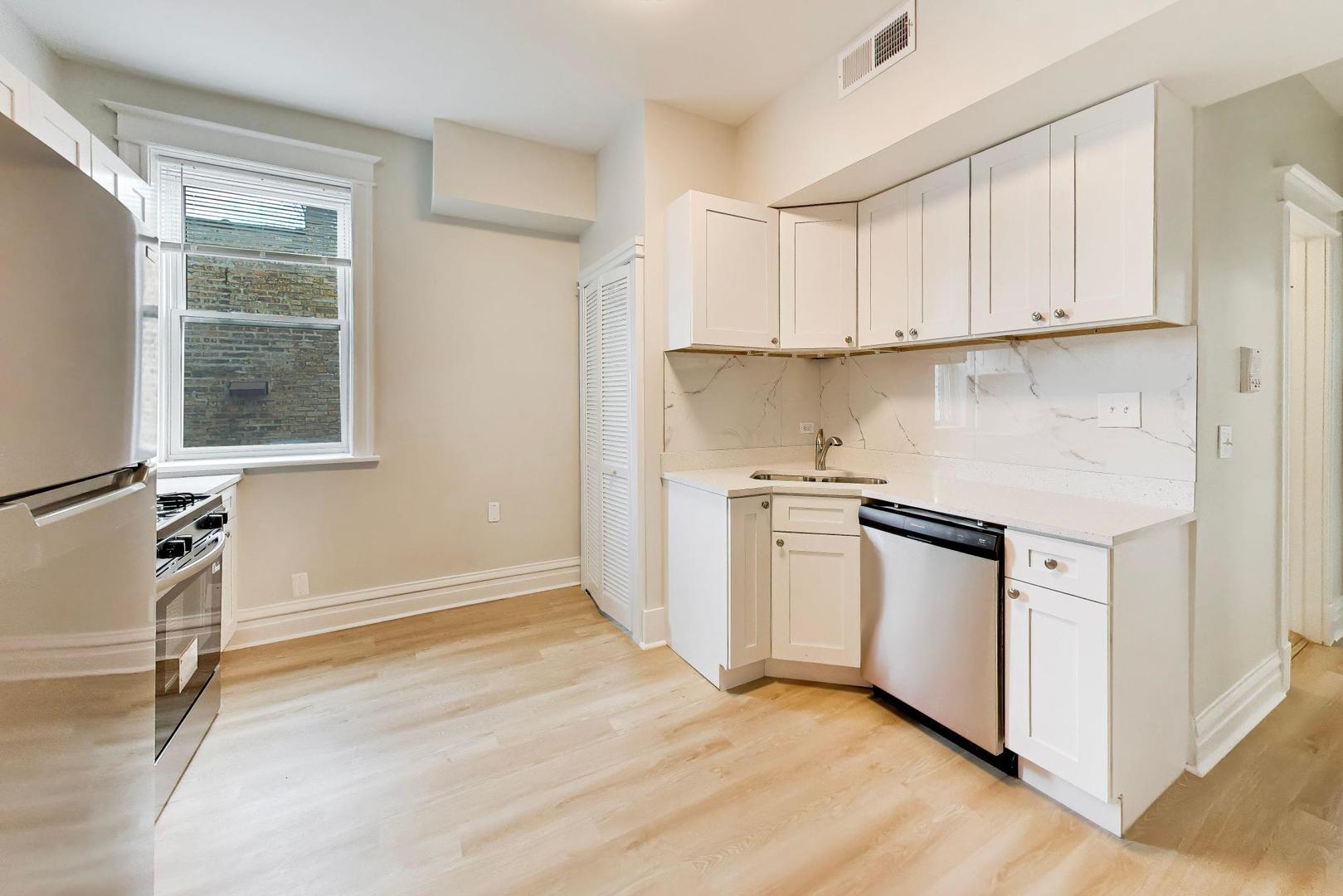 1646 West Byron Street, Unit 2F Chicago, IL 60613 - Photo 13 of 27 a kitchen with white cabinets and white appliances