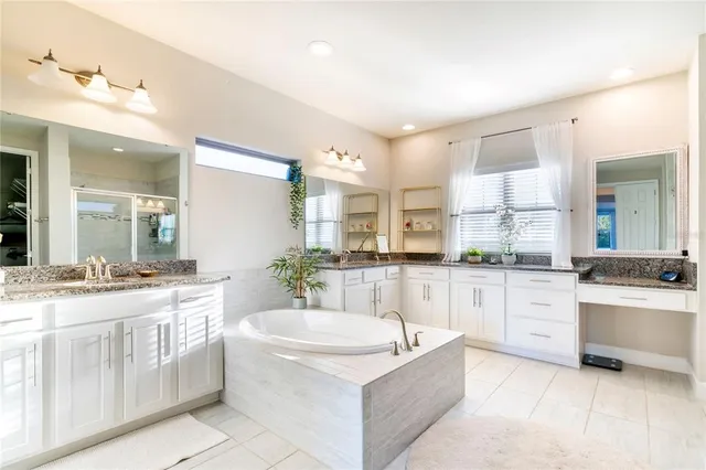 a large bathroom with a granite countertop tub sink and mirror
