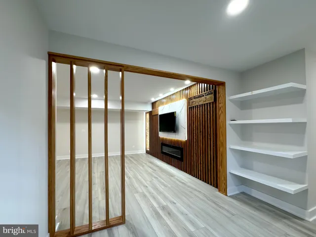 a view of a hallway with wooden floor and a bathroom