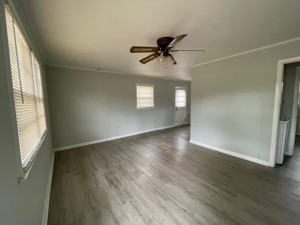 a view of empty room with wooden floor and window