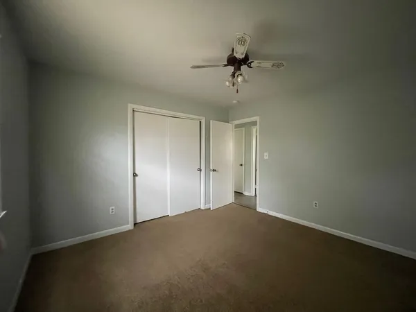 a view of a big room with a chandelier fan and windows