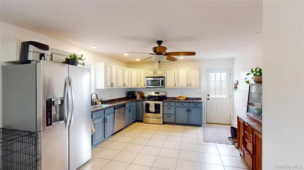 a large kitchen with stainless steel appliances granite countertop a refrigerator and a stove top oven