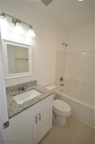 a bathroom with a granite countertop sink a toilet and shower