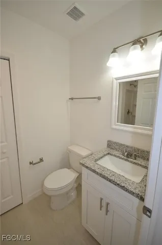 a bathroom with a granite countertop sink a toilet and a mirror