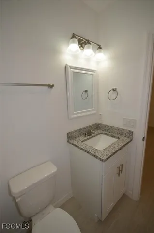 a bathroom with a granite countertop toilet sink and mirror