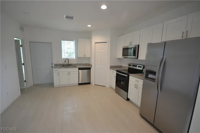 a kitchen with white cabinets and stainless steel appliances