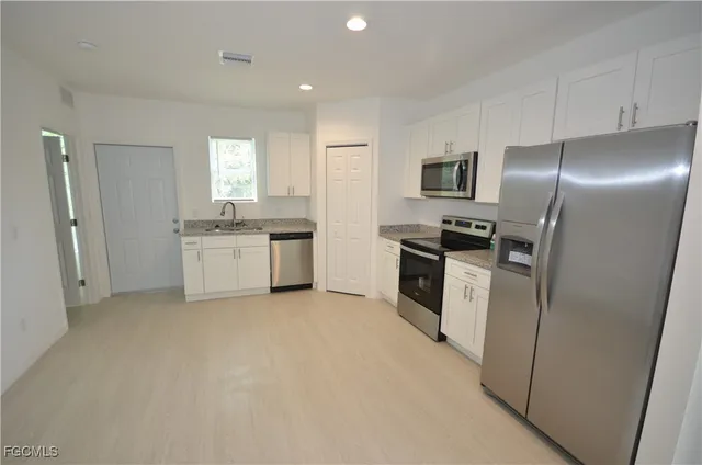 a kitchen with white cabinets and stainless steel appliances