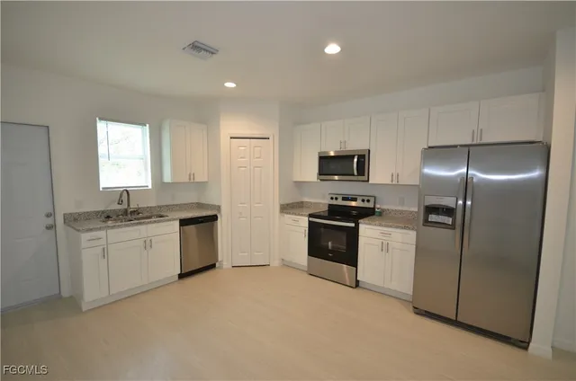 a kitchen with granite countertop a refrigerator stove and sink