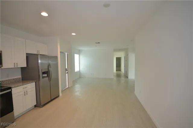 a view of a kitchen with refrigerator and white cabinets