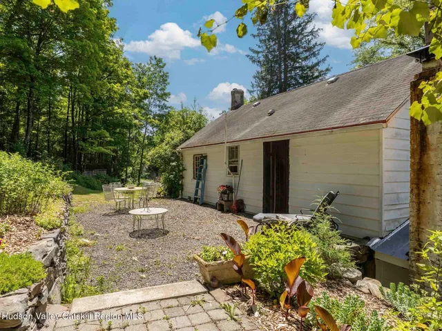 a view of a backyard with table and chairs potted plants and tree